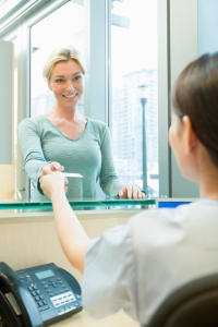 Female patient taking appointment card from receptionist at dentist's office